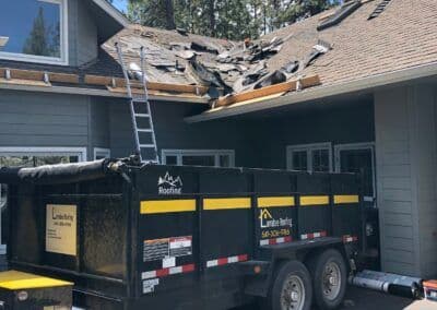 Roofing project in progress with debris on a house and a dumpster for materials.