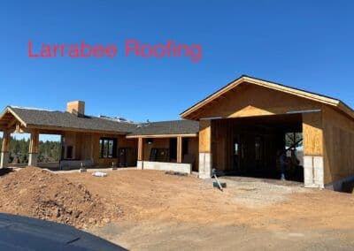 New residential construction featuring Larrabee Roofing with wood framing and clear blue sky.