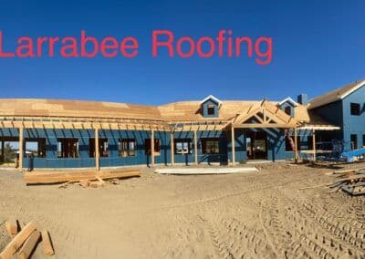 Larrabee Roofing construction site with wooden roof framing under blue sky.