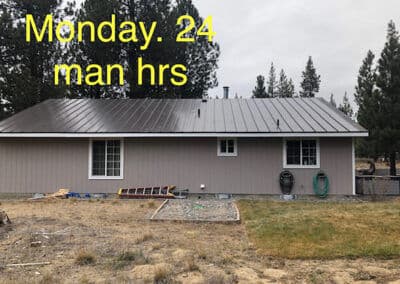 House exterior with metal roof, landscaping work, Monday, 24 man hours noted.