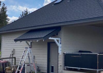 Residential home exterior with a new roof, awning, and ladder in a sunny outdoor setting.