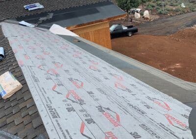 Roofing installation with waterproof underlayment on a residential building's sloped roof.