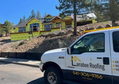 Larrabee Roofing truck parked in front of a house under construction with green insulation.