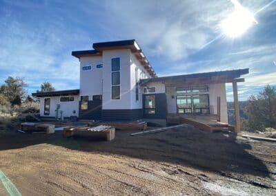 Modern house design with large windows and wooden accents in a natural landscape.