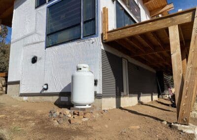 Newly constructed home exterior with propane tank and wooden deck framing.