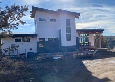 Modern hillside home design with wooden features and large windows amidst natural landscape.