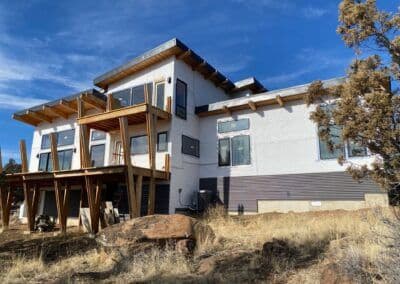 Modern two-story house with wooden deck, large windows, and desert landscaping.