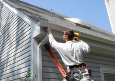Roof maintenance worker cleaning gutters on a residential home.